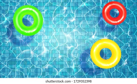 Swimming pool with floating rubber rings, blue water, ripples and highlights. Texture of water surface and tiled bottom. Overhead view. Summer background.