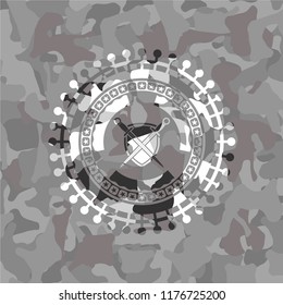 swords crossed with shield icon inside grey camo emblem