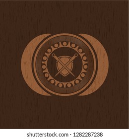 swords crossed with shield icon inside badge with wooden background