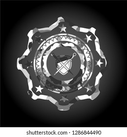 swords crossed with shield icon inside grey camouflaged emblem
