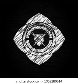 swords crossed with shield icon inside chalkboard emblem written on a blackboard