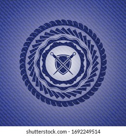 swords crossed with shield icon inside jean or denim emblem or badge background