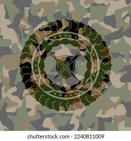 swords crossed with shield icon inside camouflage emblem. 