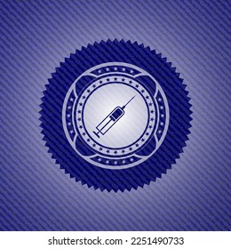 icono de la jeringa dentro del emblema con fondo de jean. 