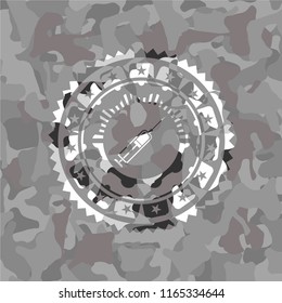 syringe icon inside grey camouflaged emblem