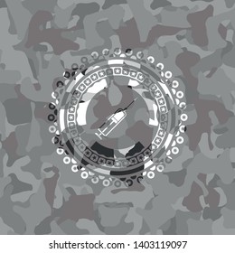 syringe icon inside grey camouflaged emblem