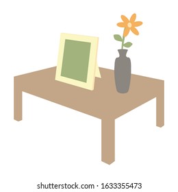 The table with flower pot that has flower inside and picture frame