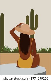 Chica de morena con sombrero se baña al aire libre alrededor de la vegetación y el cactus