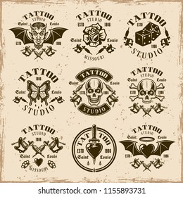 Tattoo studio set of nine vector emblems, labels, badges or t shirt prints in vintage style on dirty background with stains and grunge textures