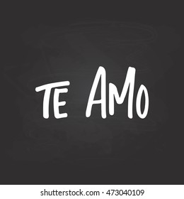 Te amo - I love you, lettering calligraphy phrase in Spanish, handwritten text isolated on the black chalkboard background. Fun calligraphy greeting and invitation card or t-shirt print design.