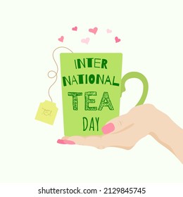 Tea cup with tea on the palm and the inscription to the International Tea Day
