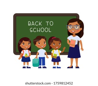 Teacher greeting pupils in classroom flat vector illustration. Boys and girls dressed in school uniform and female teacher pointing at blackboard cartoon characters. Primary students back to school