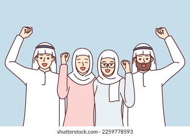 Team of people in arabic clothes make victory gestures rejoice at startup success. Modern men and women in Islamic clothing and headdresses raise their fist up with smile