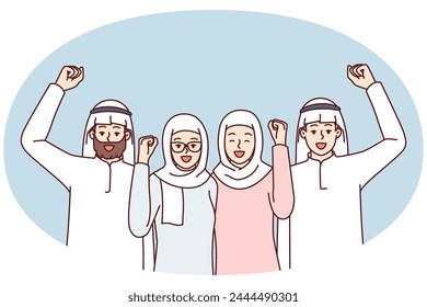 Team of people in arabic clothes make victory gestures rejoice at startup success. Modern men and women in Islamic clothing and headdresses raise their fist up with smile