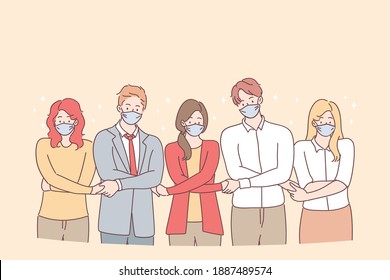 Teamwork, unity, protective masks during coronavirus pandemic concept. Young people business partners or creative colleagues standing and holding hands as symbol of uniting efforts and common goal 
