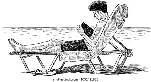 A teen boy reads a book on a beach