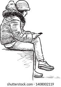 A teen girl sits on a street bench with her mobile phone