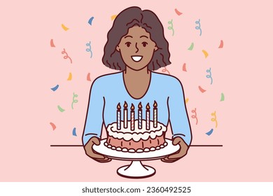 Muchacha adolescente con pastel de cumpleaños en las manos se pone entre canfeti y sonrisas, ofreciendo celebrar fiesta de fiesta. Niño afroamericano sosteniendo pastel de cumpleaños con velas calientes y mirando la pantalla