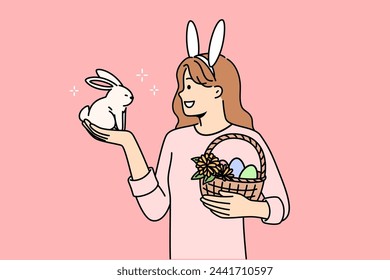 Teenage girl celebrating easter holds decorated eggs in basket and small rabbit, rejoicing at coming of spring. Schoolgirl is preparing for easter and bringing traditional gifts to friends from school