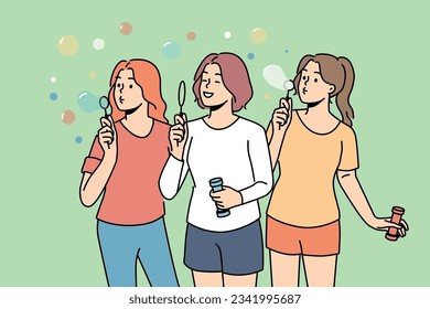 Teenage girls inflate soap bubbles enjoying outdoor recreation in hot summer weather. Three high school girls love to hang out and have fun playing in park, for concept of carefree childhood