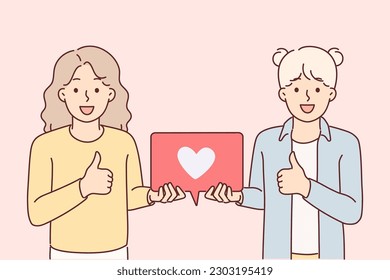 Teenage girls showing thumbs up and holding like icon for social media feedback concept. Little bloggers offer to put like under post or publication on site, demonstrating poster with heart