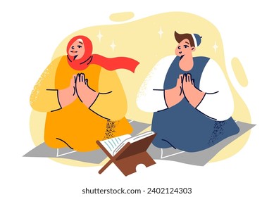 Teenage muslim boy and girl pray in mosque on knees near holy book of koran on eve ramadan. Children become familiar with islamic religion and arab culture by doing traditional ritual during ramadan