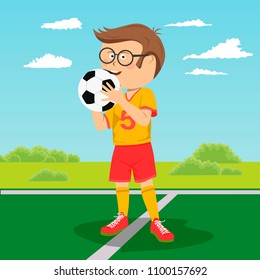 Teenager boy with glasses poses with soccer ball on field