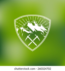 Template for logos, labels and emblems with mountains, two ice axes and sunbeams. Vector illustration.