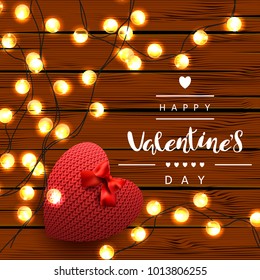 Template square festive wooden plank background. A knitted red heart with a bow and Garland. Inscription lettering "Happy Valentine's Day." Vector. View from above.