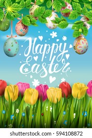 Template vector card with realistic colorful eggs, grass and tulips. Handwriting inscription Happy Easter. Sunny green background.  Foliage. Lettering, calligraphy. 3D. Decorated eggs hang on a tree.
