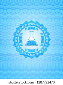 test tube icon inside light blue water wave badge background.