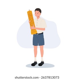 thai schoolboy holding large wax candle for buddhist holiday celebration in thailand cultural festival and asian tradition.