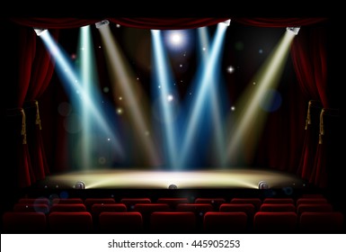 A theatre or theater stage and audience seating with footlights, spotlights and red curtains