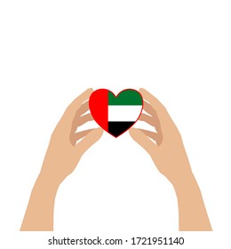 There are two hands holding a heart carefully isolated on white background. The heart is contained UAE flag inside. Concept about love, care and hopefully.