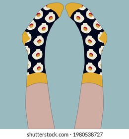 They wear socks with a print of scrambled eggs on their feet. The girl lies with her legs raised and looks at her socks. Black socks, blue background