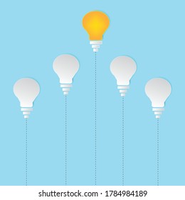 Think different concept One Yellow light bulb standing out from the dim white light bulbs on white wall background
