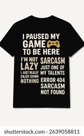 This image displays a black t shirt featuring a humorous, multi line graphic print in a cream tan color, with a small yellow game controller icon.