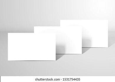 Three blank white business cards or postcards stand one after another on the surface. Mockup for design with a realistic shadows