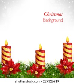 Three burning Christmas candles with pine branches and flowers of poinsettia in snowfall on grayscale background