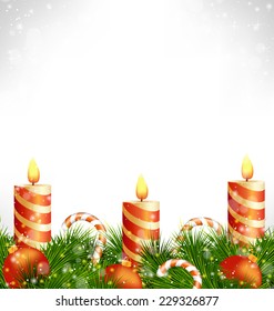 Three burning orange Christmas candles with Christmas balls, candy canes and pine branches in snowfall on grayscale background