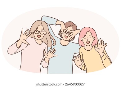 Three happy girls of friend have fun making funny faces and putting fingers to faces instead of glasses. Positive women dressed in casual clothes pose together for commemorative photo