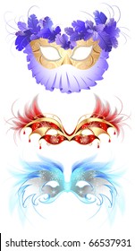 three luxury masquerade masks, decorated with elegant decor and fluffy red and blue feathers.