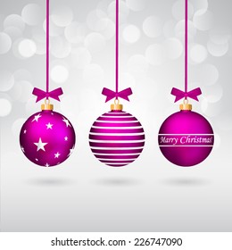 Three purple different decorated christmas balls with bows on sparkling background.