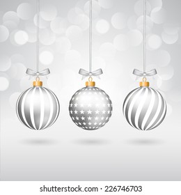 Three silver different decorated christmas balls with bows on sparkling background.