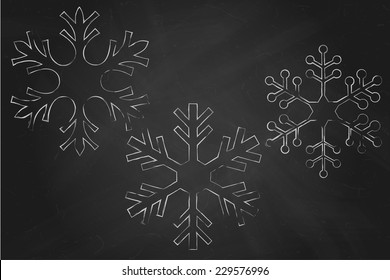 Three white chalk snowflakes over black chalkboard.