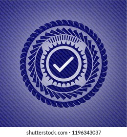 tick icon inside emblem with jean background