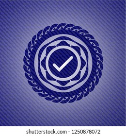 tick icon inside emblem with jean background