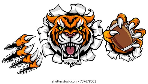 A Tiger angry animal sports mascot holding an American football ball and breaking through the background with its claws