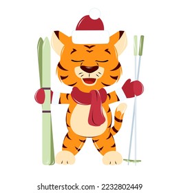 a tiger cub in a red New Year's hat, scarf and mittens stands with skis and ski poles 