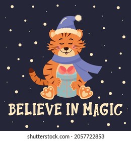 Tiger in santa hat and scarf is sitting with a gift. Believe in magic lettering.  Winter greeting card.